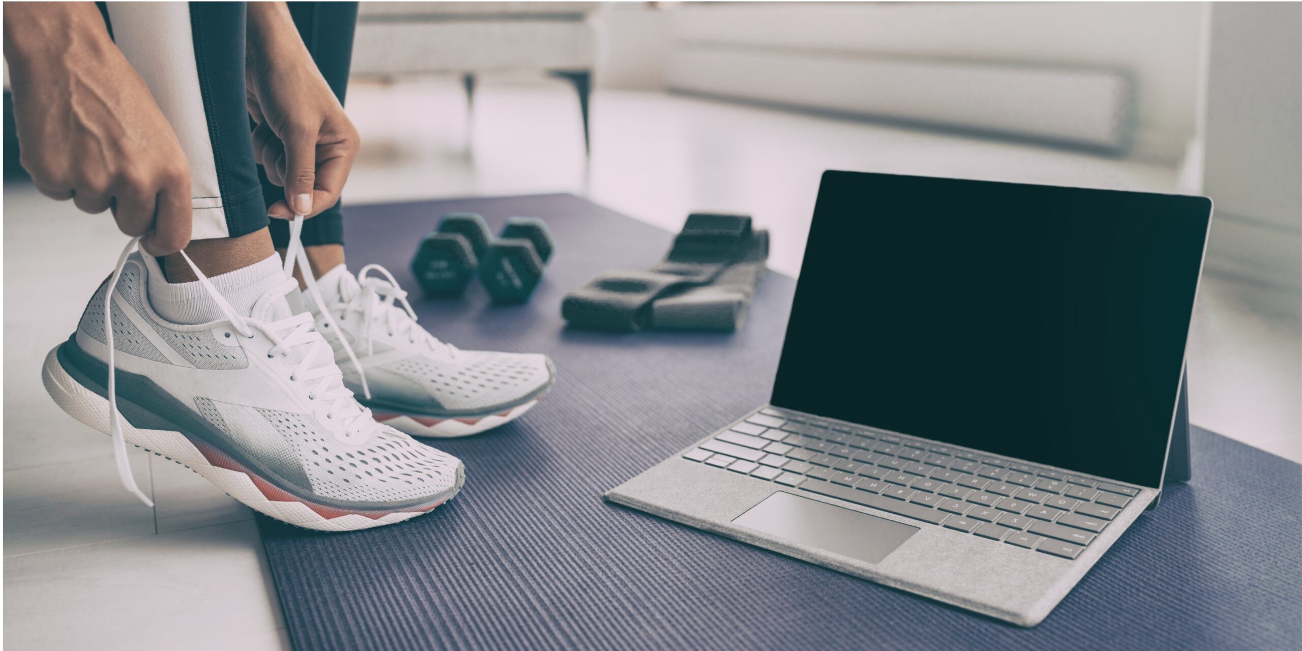 laptop on the floor and a pair of women's trainers with sports equipment in the background.